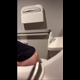 A hidden camera records an unsuspecting girl from behind as she sits on a toilet in a public restroom and takes a shit. You can see her seated rear view throughout, and bathroom audio is audible. Vertical format video. About 2.5 minutes.